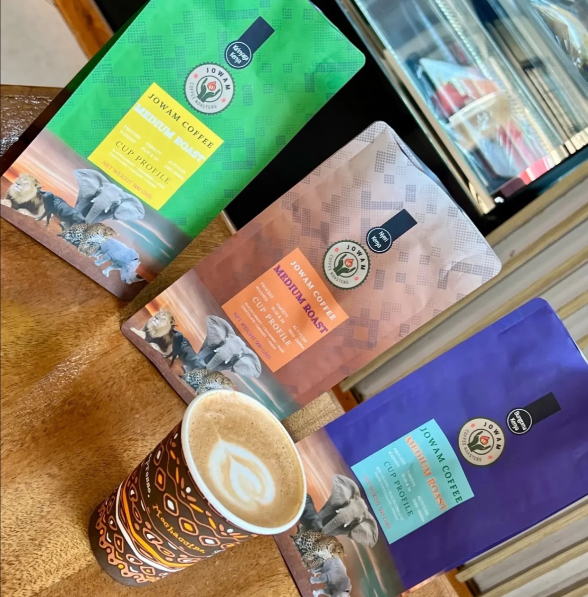Bags of Jowam coffee beside a latte